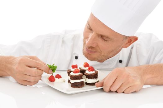 Baking, presentation and chef with a dessert for catering isolated on a white background. Cooking, professional and man plating a chocolate cake and fruit on a plate for service on a backdrop