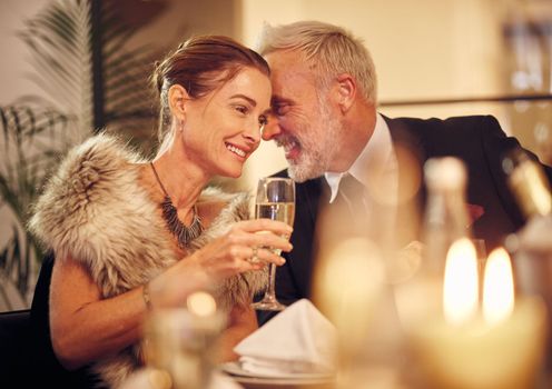 Woman, man and whisper at dinner, party or restaurant for celebration in night with smile, happy and gossip. New year, fine dining or gala event with champagne, conversation and romantic secret love.