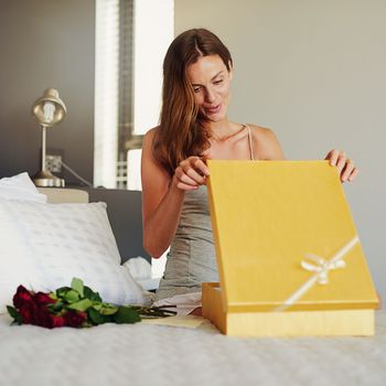 Ooh, I love it. a young woman opening a surprise gift at home.