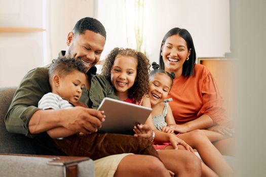 A happy mixed race family of five relaxing on the sofa at home. Loving black family being affectionate on the sofa while using a digital tablet and streaming. Young couple bonding with their kids and