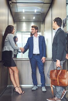 Conferences are for conversations and connecting. businesspeople meeting and greeting in an elevator.