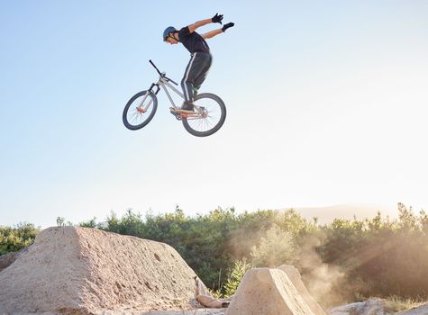 Bike, man and extreme jump at park, safety gear and outdoor for rush, competition and training for stunt. Bicycle, male athlete or dirt bike practice for fitness, contest or motivation for tournament
