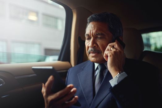Creating success wherever he goes. a mature businessman using a phone and digital while traveling in a car.