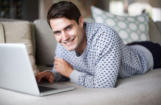 Bet you want to play on my laptop. Portrait of a handsome young man smiling at the camera with his laptop in front of him.