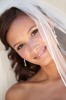 Beautiful and softly elegant. Beautiful bride smiling while wearing her veil.