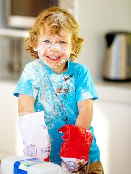 The future of the culinary arts. A little boy covered in dough and flour.
