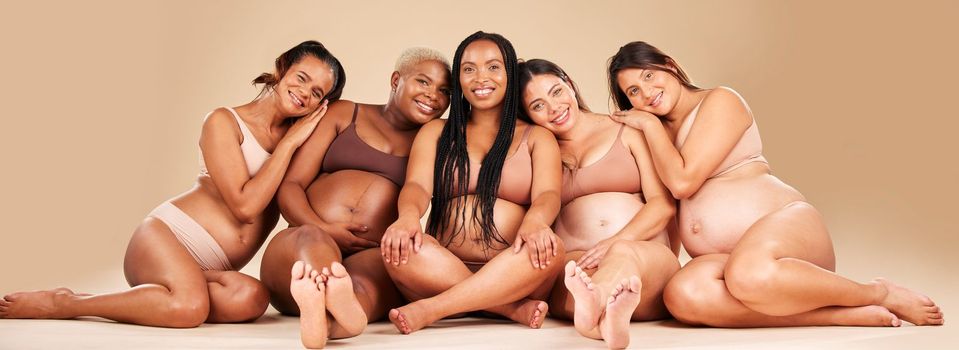 Portrait, hug or sitting pregnancy friends in underwear for community bonding, diversity support or body empowerment. Happy smile, floor or pregnant women in healthcare wellness, future baby or love