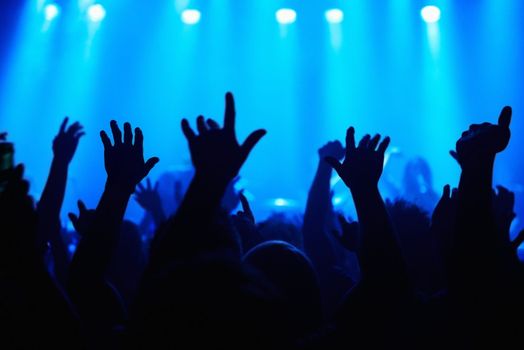 Music brings us together. A crowd of people watching a band play on stage at a nightclub