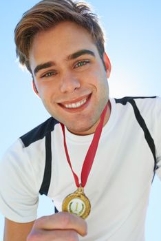 I always aim for the gold. Smiling medal winner holding his award proudly.