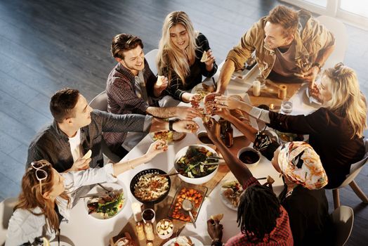 Food is our favorite reason to get together. a group of young friends making a toast at a dinner party