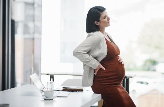 Stress isnt just bad for you but for baby too. a pregnant young businesswoman feeling unwell while working in a modern office.