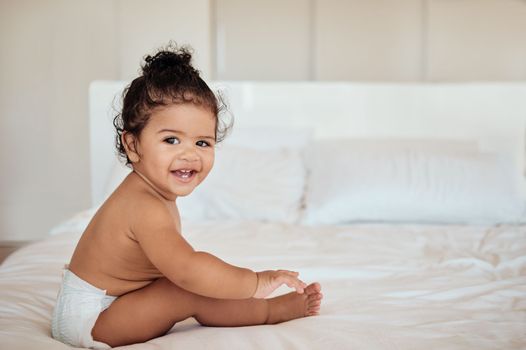 Happy, health and baby on bed portrait in diaper with wellness, cheerful and cute smile in home. Relax, happiness and healthy toddler in disposable napkin and barefoot in house bedroom.