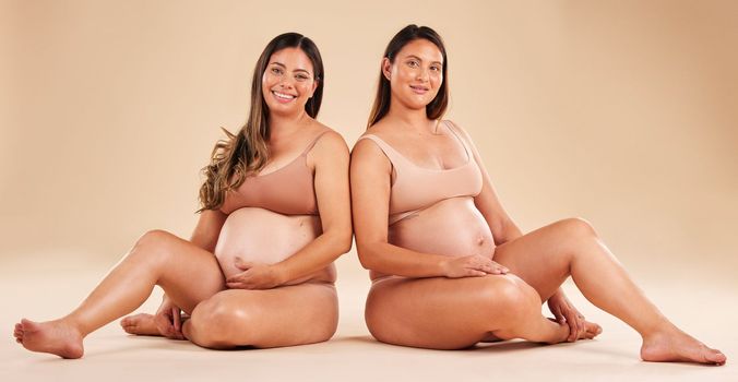Women, portrait or sitting with pregnant stomach, tummy growth progress or baby healthcare wellness on studio background. Smile, happy or friends in pregnancy underwear for solidarity support or love
