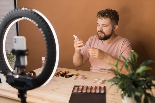 Famous blogger. Cheerful male vlogger showing cosmetics products while recording video and giving advices for his beauty blog. Make-up artist and recording beauty vlog