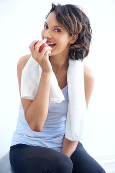 Your diet is more than half the work. A healthy young beauty enjoying a crunchy apple after a workout.