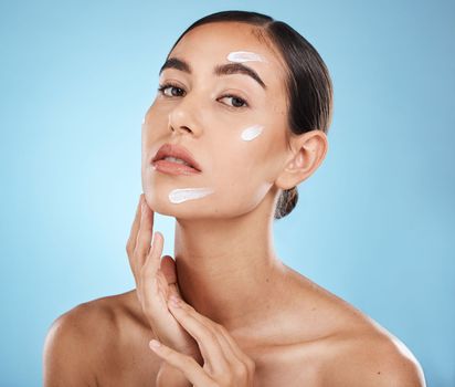 Skincare cream, face portrait and woman in studio isolated on a blue background. Cosmetics, dermatology and young female model with lotion, creme or moisturizer for beauty, aesthetics and wellness.