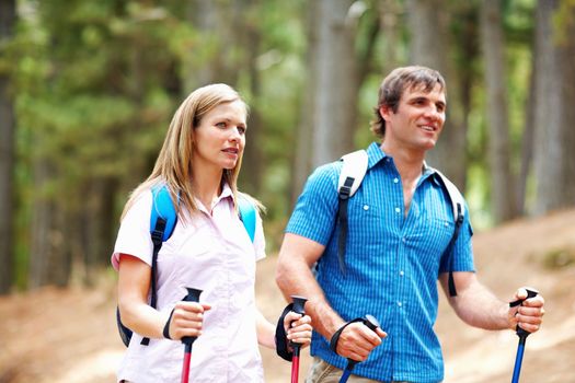 Couple hiking. Cute couple with backpack walking with hiking poles.