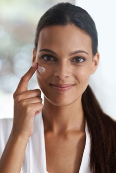I invest in quality skin care products. Closeup portrait of a gorgeous young woman applying moisturizer to her skin.