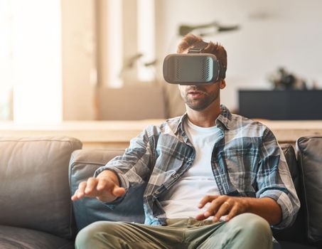 Entertainment for all the senses. a young man using a virtual reality headset on the sofa at home.