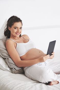 Preparing herself for a special delivery. a pregnant woman using a digital tablet at home.