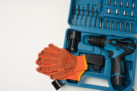 plastic box with cordless drill and set of drills and screwdrivers on white background