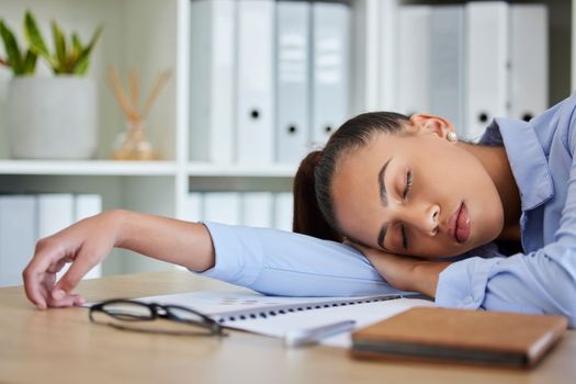 Tired, sleep and woman in business on her table feeling burnout and overworked while sleeping in her office. Nap, dreaming and exhausted with fatigue businesswoman napping on her table at work