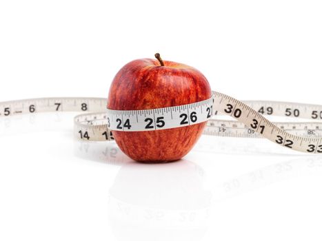 Make the healthy choice. Studio shot of a red apple with measuring tape wrapped around it.