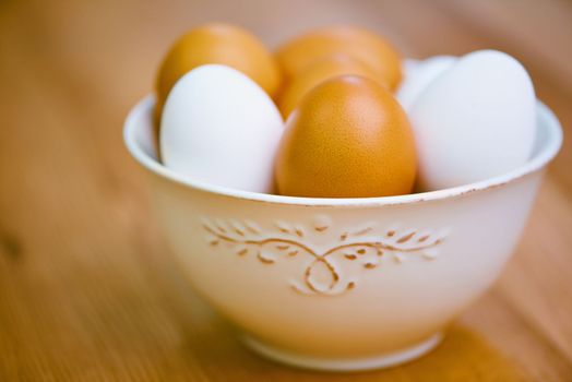 All in one bowl. a bowl of white and brown eggs on a wooden table.