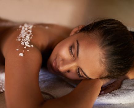 She couldnt think of any place shed rather be. a young woman enjoying a salt exfoliation treatment at a spa.