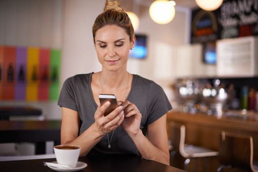 I should have a degree in texting by now. An attractive woman texting while sitting at a coffee shop.