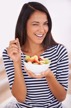 Wink if you love a healthy snack. Portrait of a young woman eating fruit salad.