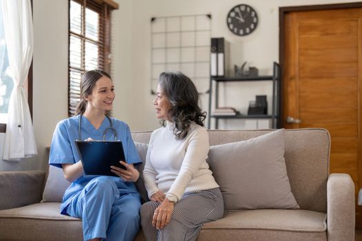 Nurse taking notes during home visit with senior female patient