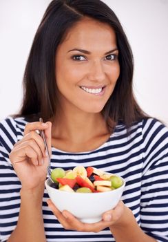 Now this is what I call healthy eating. Portrait of a young woman eating fruit salad.