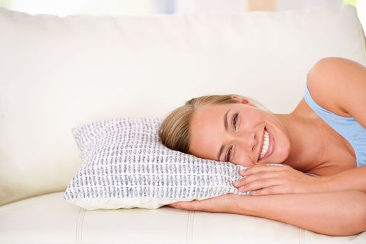 Ready for a nap on the sofa. Portrait of an attractive young woman resting her head on a pillow while lying on the sofa.