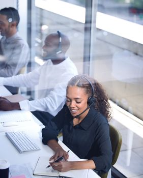Call center, customer support with a happy black woman consultant working in her telemarketing office. Contact us, crm and communication with a female consulting using a headset from above.