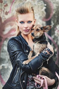 The only pet for a rockstar like me. Cropped portrait of an edgy young woman holding her small dog in an urban setting.