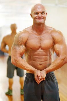 He has worked hard to look this way. a male bodybuilder flexing his muscles at the gym.