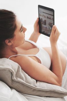 Taking it easy before baby arrives. a pregnant woman using a digital tablet at home.