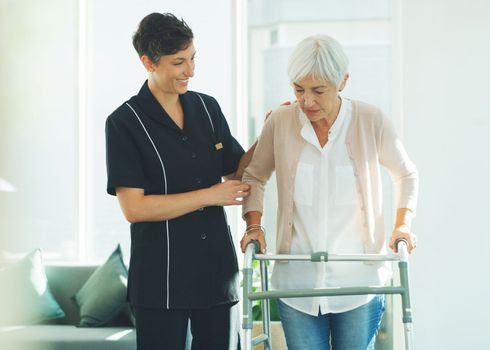 Please help me. an attractive young healthcare professional helping her senior patient walk with a walker in a nursing home