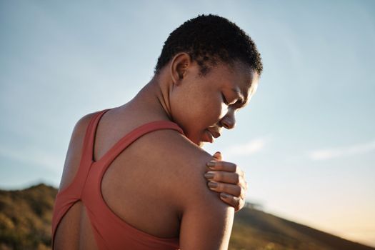 Shoulder, black woman and exercise injury from outdoor sports training on sky background. Athlete, arm and joint pain, muscle problem and first aid emergency from wound, fitness and workout mistake