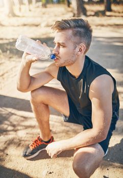 Fitness makes you thirsty. a young man drinking water while out for a workout.
