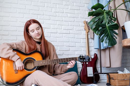 Young woman playing guitar at home