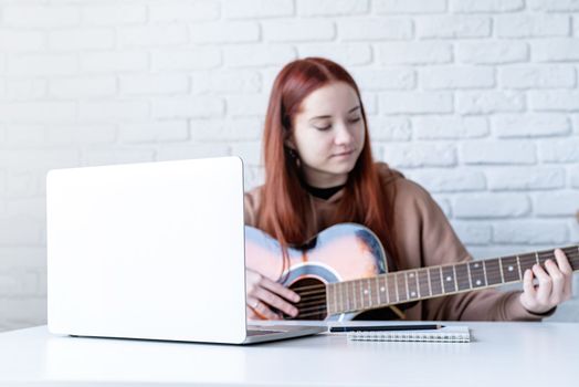 Young woman learning to play guitar at home