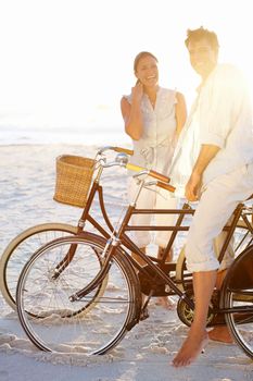 Biking on the beach together. A mature couple enjoying a bike ride on the beach together.