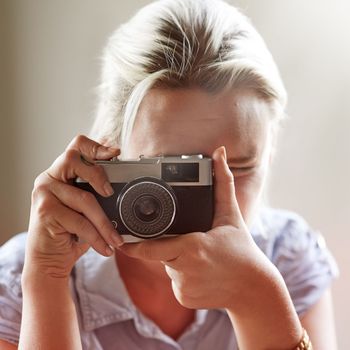 Capturing life. Closeup shot of a young woman taking a photograph with an old-fashioned camera
