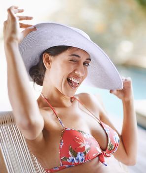 Shes in summer mode. Portrait of a young woman in a bikini winking at the camera.