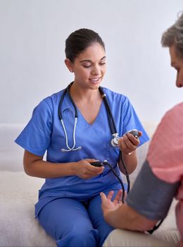 Lets take a look at your blood pressure reading...a nurse checking a senior patients blood pressure.