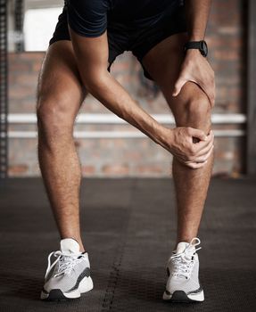 Knee injury, pain and fitness with a sports man holding his joint during a workout routine in the gym. Anatomy, accident and exercise with a male athlete injured while training in a health club