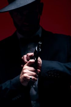 Gangster, hands or cocking gun on studio background in dark secret spy, isolated mafia leadership or crime safety. Model, assassin or hitman weapon in ready, formal style or fashion clothes aesthetic