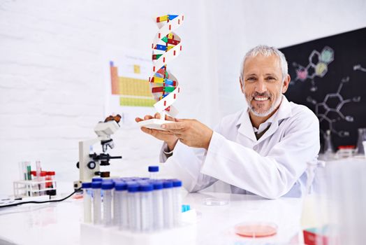 Youve got to love scientific progress. Portrait of a mature male scientist holding a model of a DNA molecule in his lab.